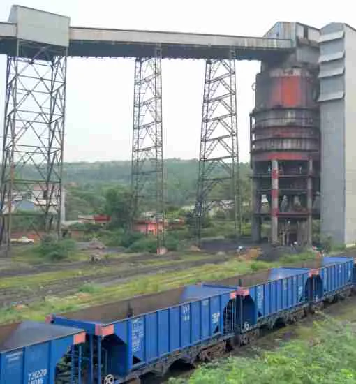 A mineral processing plant with conveyor gantries and rail wagons at a mine site